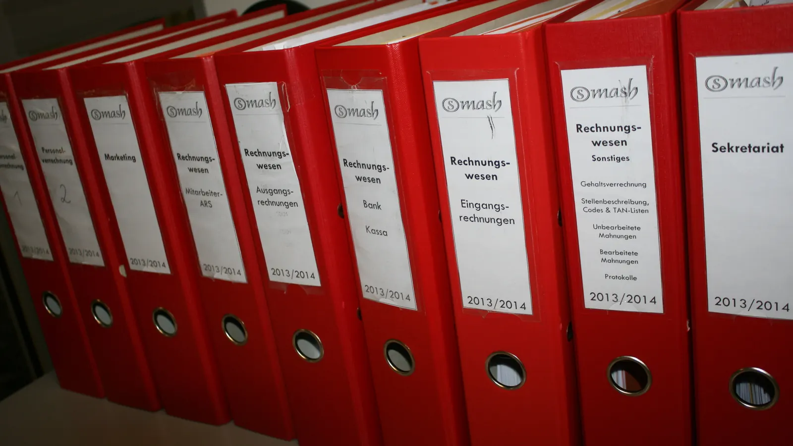 Φωτογραφία με σειρά από κόκκινους φακέλους λογιστηρίου σε ράφι