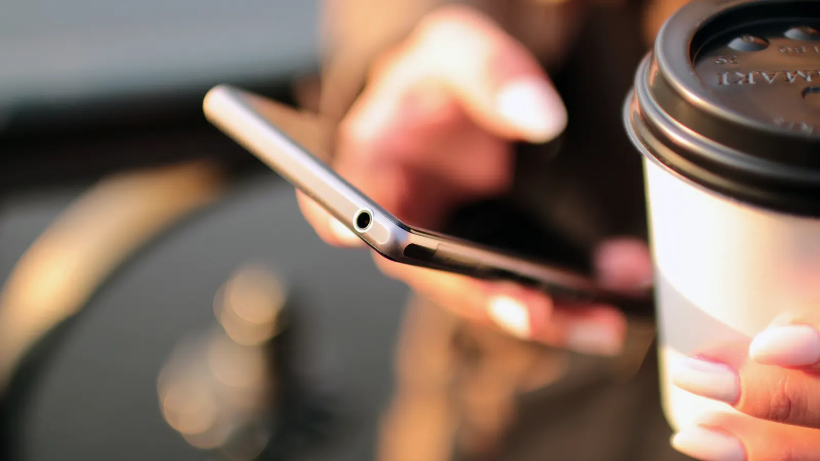 Φωτογραφία με χέρια που κρατούν smartphone και ποτήρι καφέ, για πληρωμή με το κινητό
