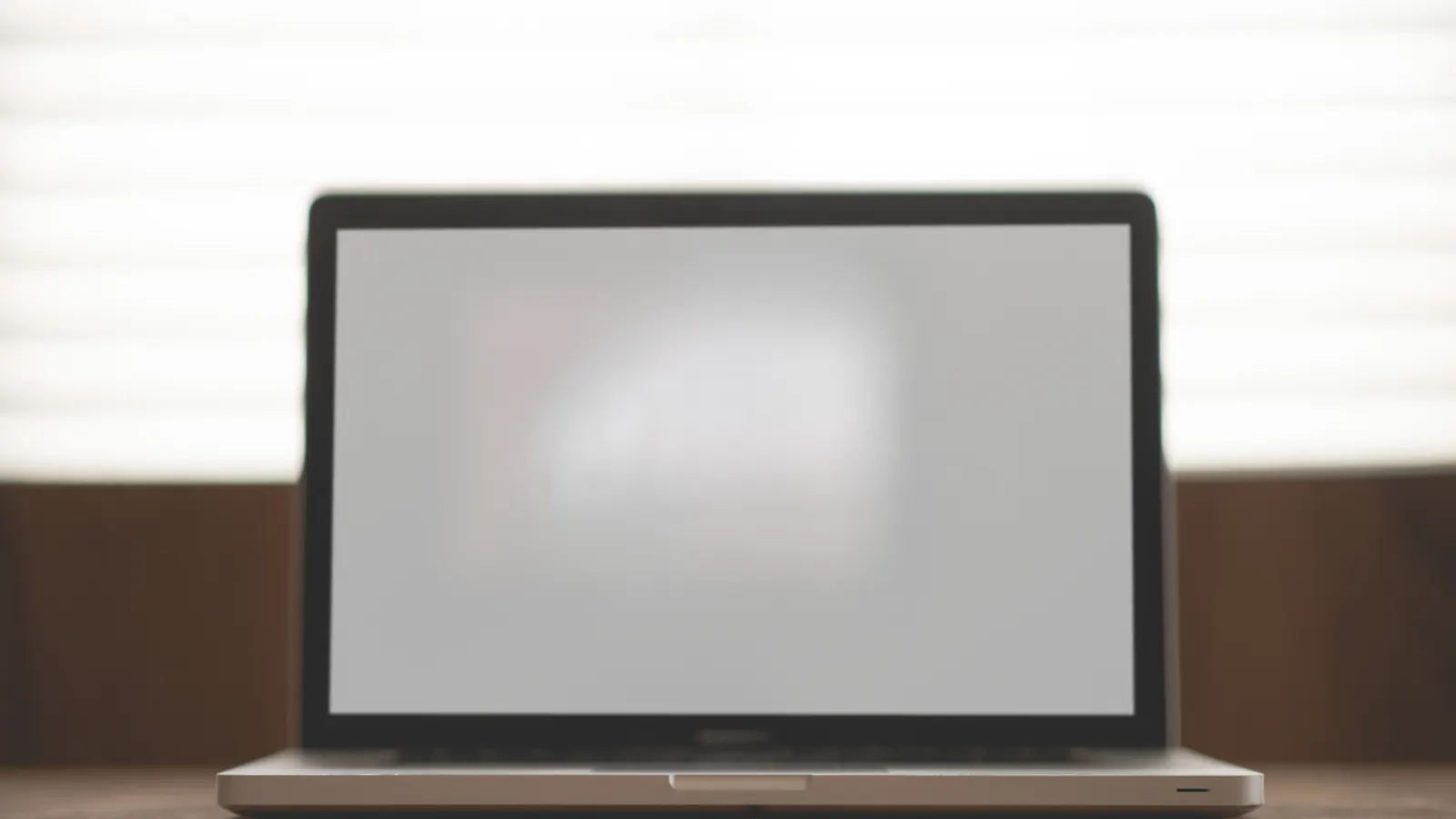 Φωτογραφία ανοιχτού laptop πάνω σε ξύλινο γραφείο μπροστά σε φωτεινό παράθυρο