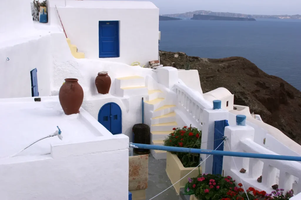 Φωτογραφία με ασβεστωμένο λευκό σπίτι με μπλε πόρτα και σκάλα πάνω από τη θάλασσα