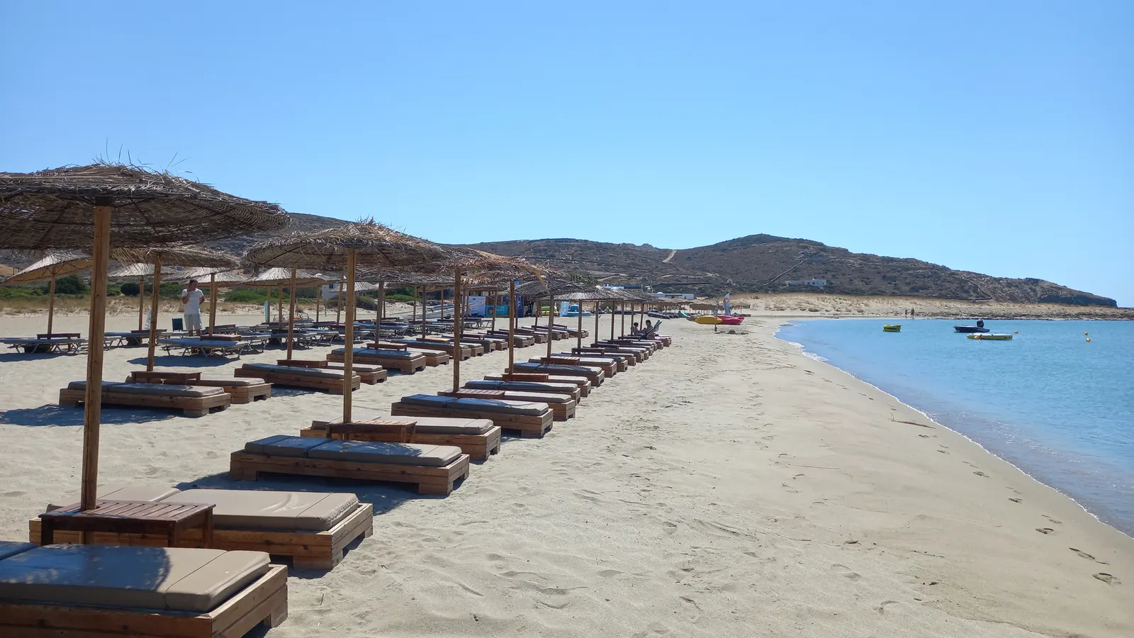 Φωτογραφία άδειας παραλίας με ψάθινες ομπρέλες και ξαπλώστρες στη Μαγγανάρη της Ίου