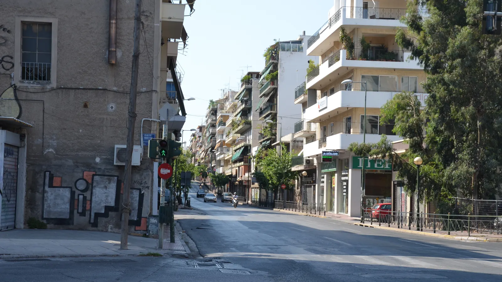 Φωτογραφία πολυκατοικιών με μπαλκόνια σε δρόμο της Αθήνας μια ηλιόλουστη μέρα