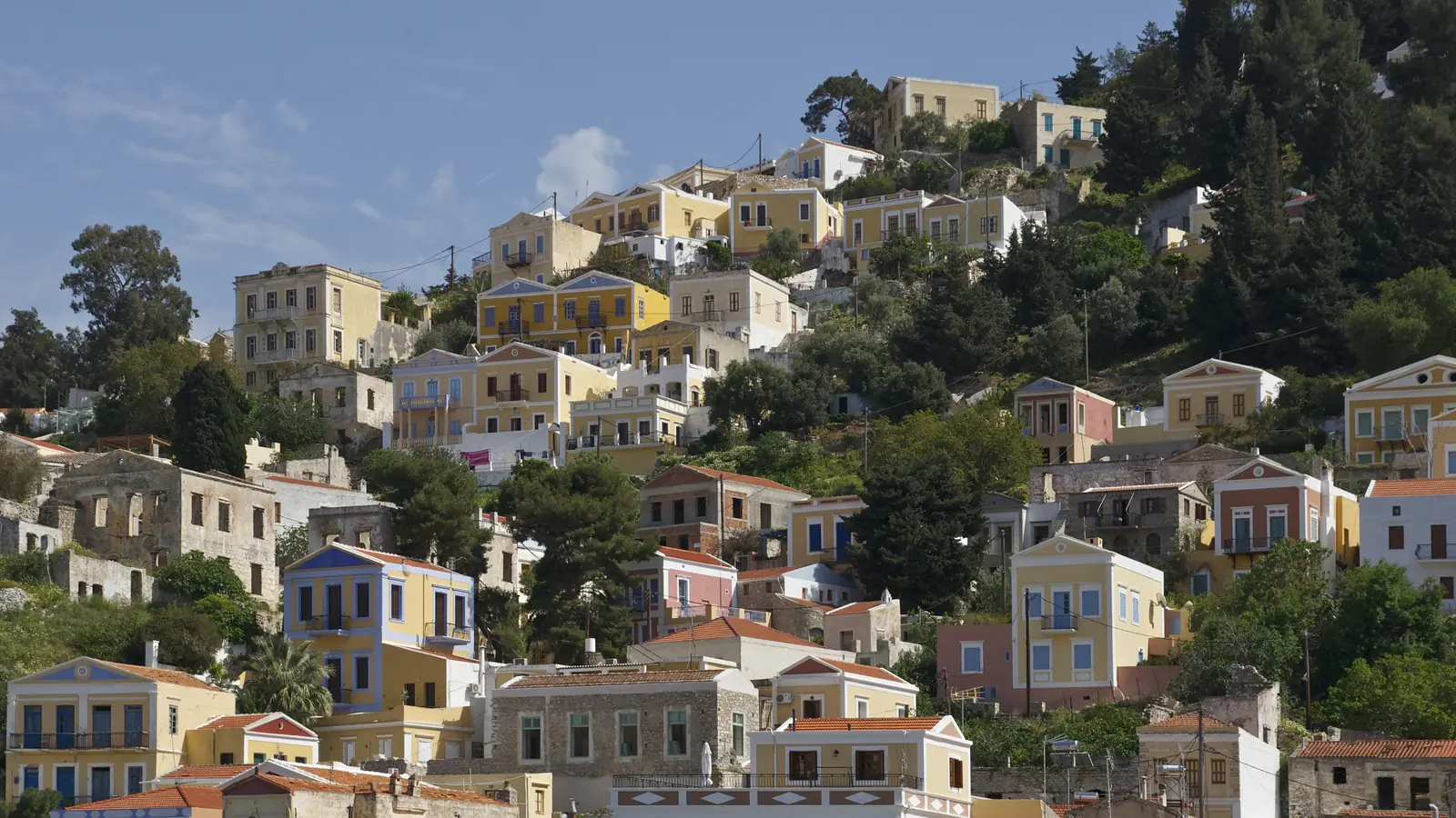 Φωτογραφία με πολύχρωμα νεοκλασικά σπίτια στην πλαγιά της Σύμης